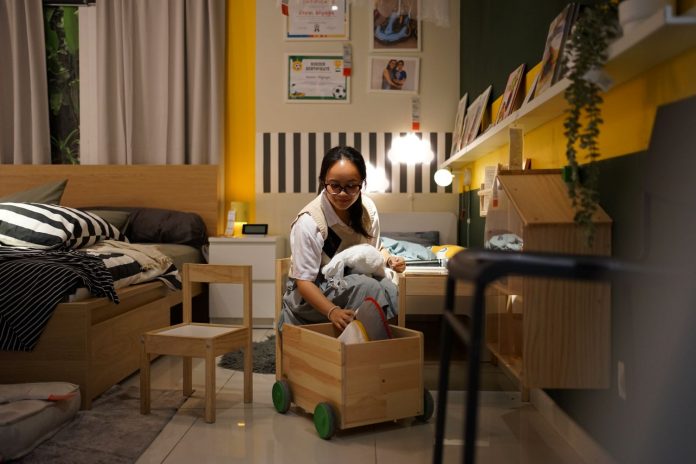 Seseorang sedang merapikan kamar tidur dengan menerapkan sistem penyimpanan yang tepat